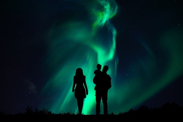 Family silhouette under Aurora Borealis